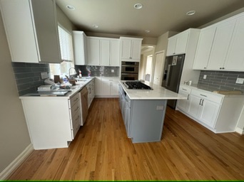 spacious kitchen design by bb-builders pro with white cabinetry, gray countertops, and hardwood floors.