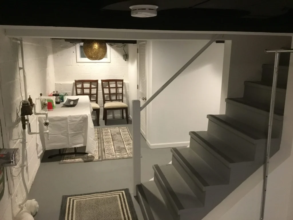 finished basement with staircase, small nook, and table setup in a modern, clean design.