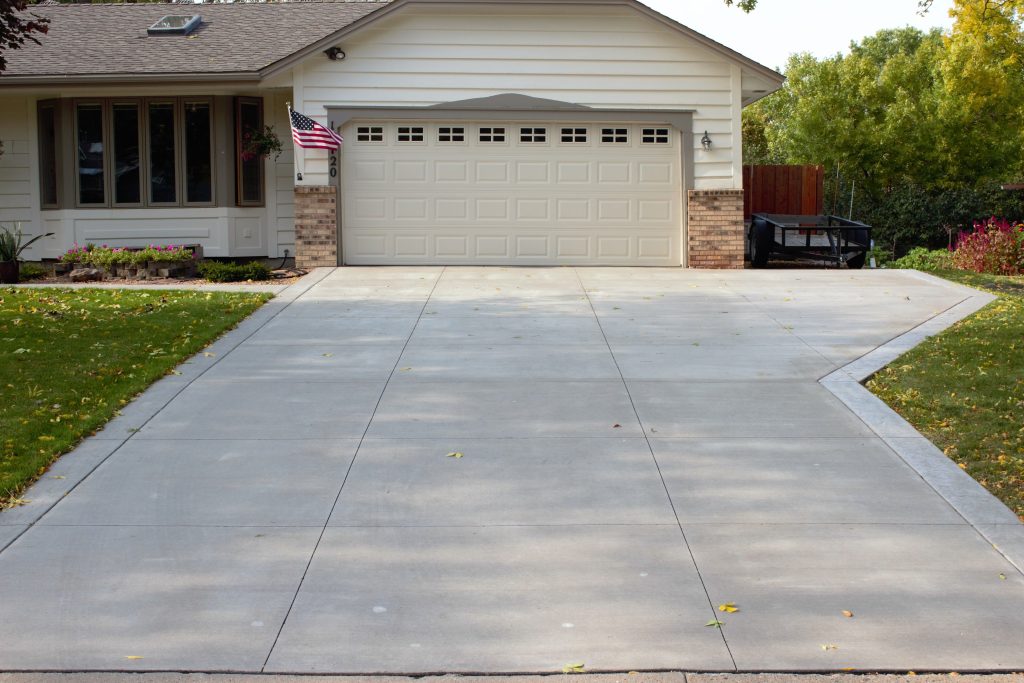 freshly poured concrete driveway leading to a two-car garage of a suburban home.