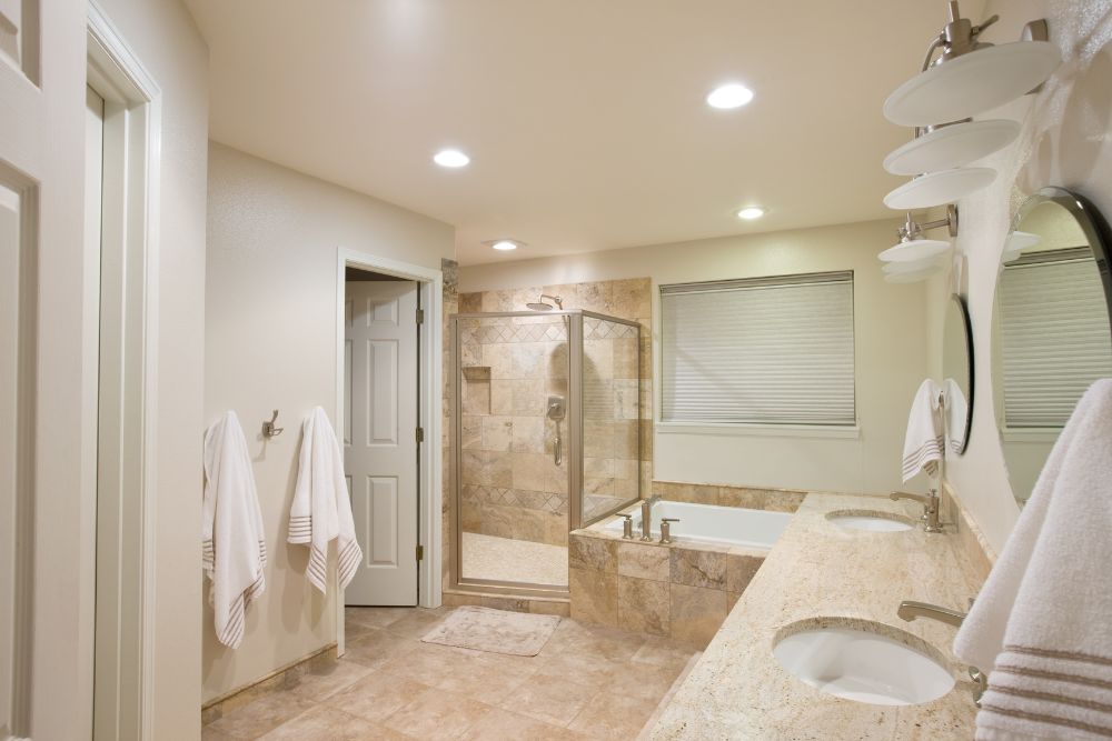 luxury bathroom remodel with stone tiles, stone vanity countertop, and task lighting
