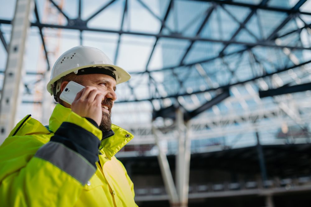 a contractor wearing a hard hat answering the phone.