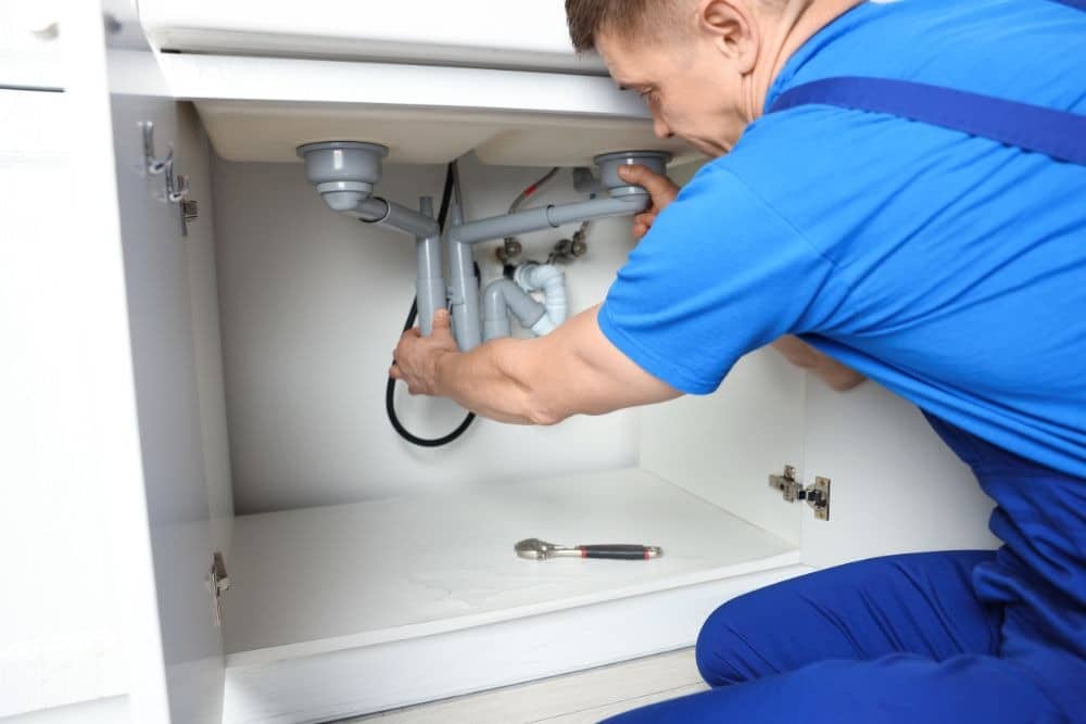 plumber fixing the undersink pipes