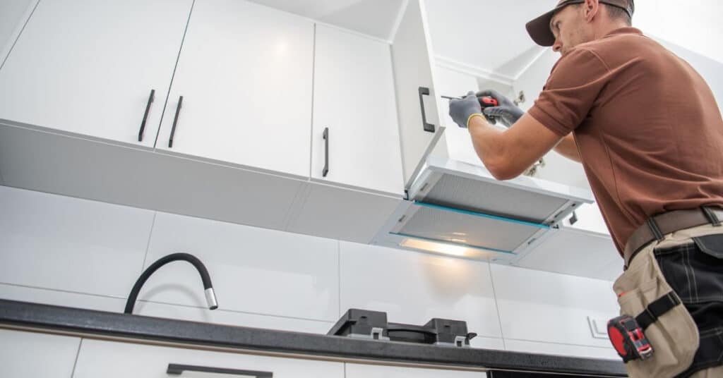man repairing an overhead kitchen cabinet