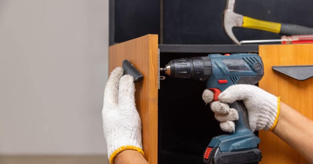 using a power tool to repair a cabinet door
