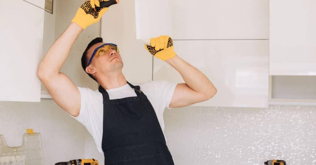 cabinet repair professional inspecting an overhead kitchen cabinet