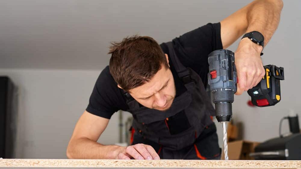 man drilling on a wood board