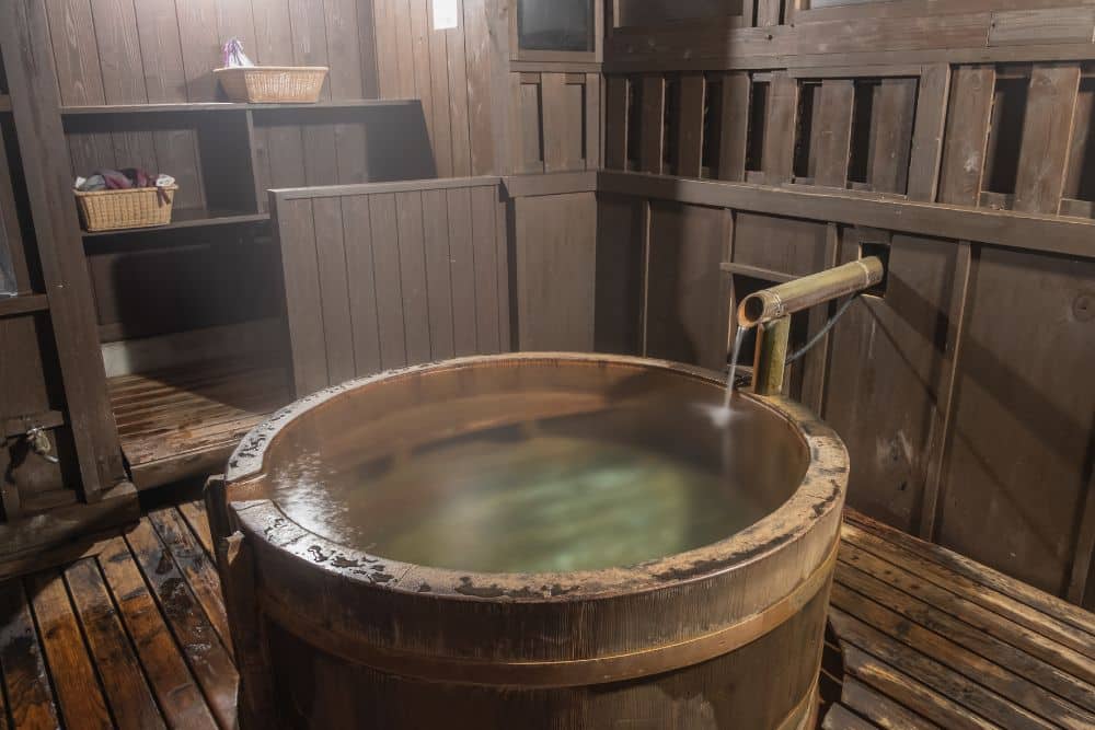 a traditional wooden ofuro or japanese soaking tub in a wooden japanese-themed bathroom