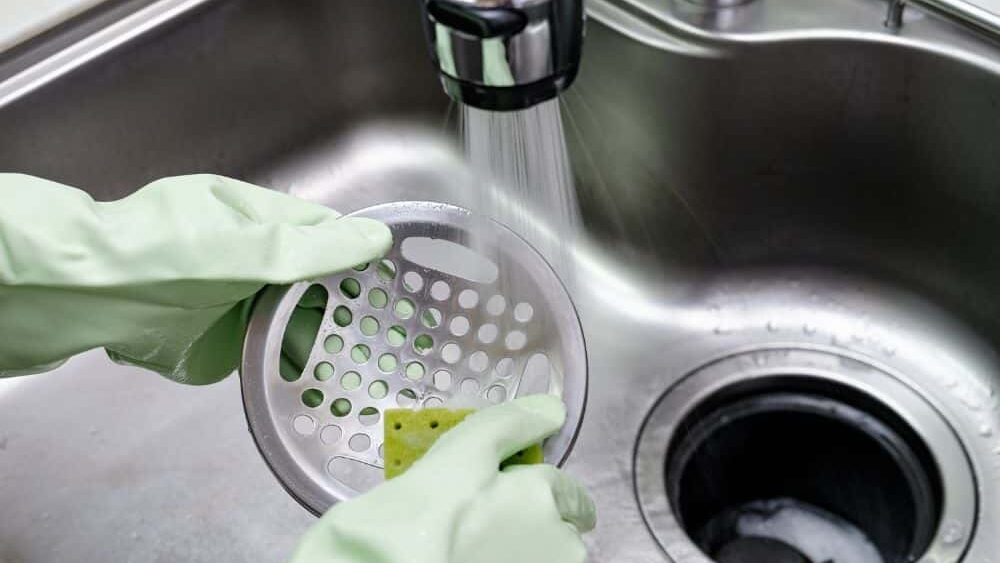 a person wearing gloved cleaning the kitchen sink