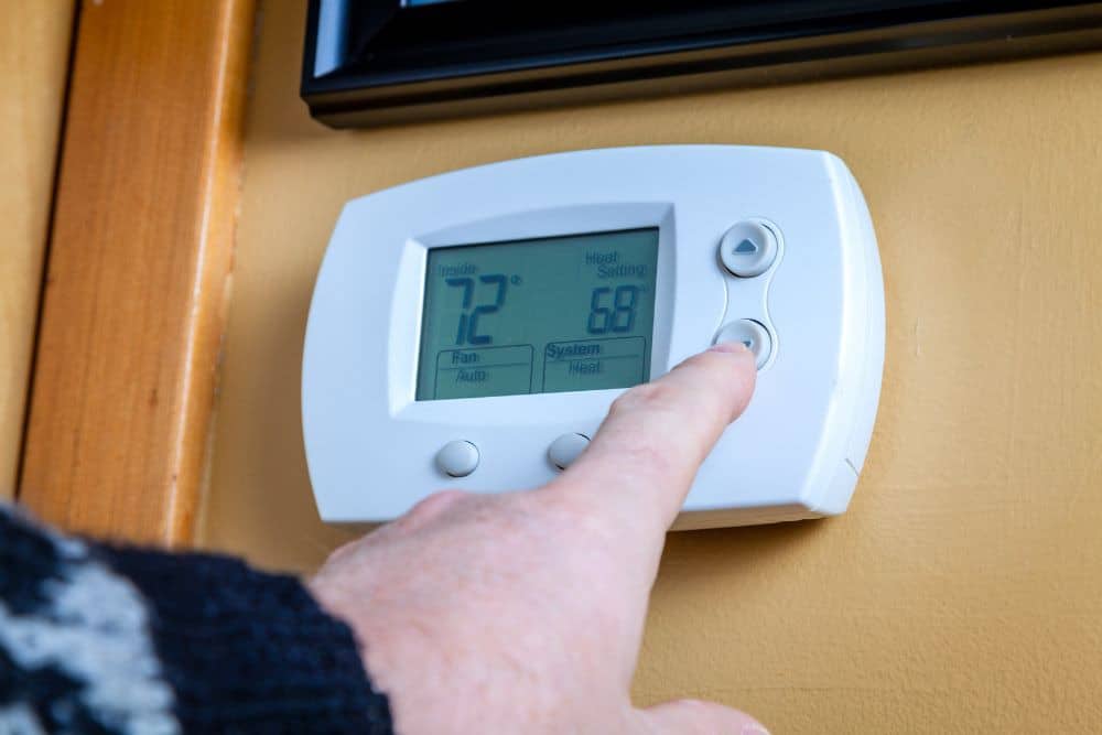 person adjusting a bathroom wall thermostat
