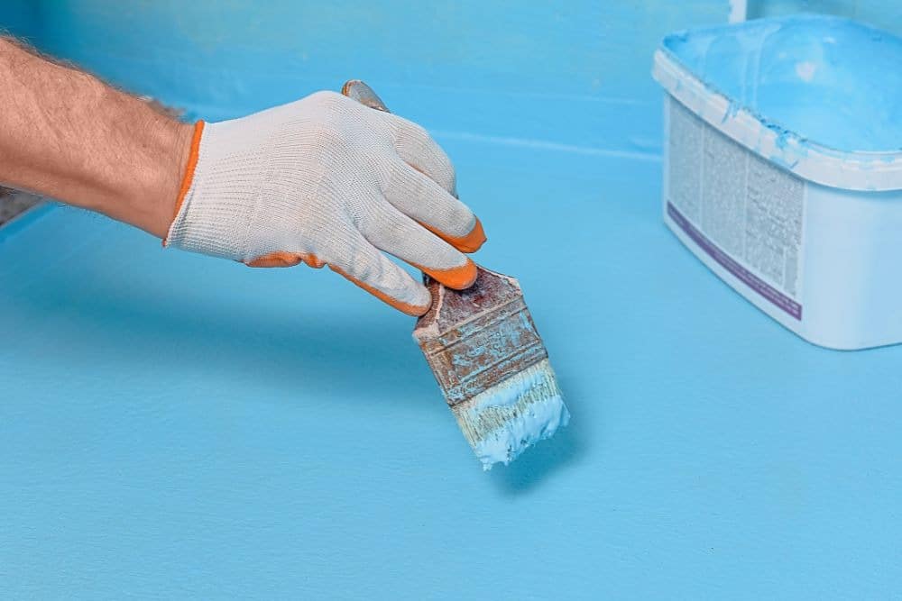 person applying waterproofing a bathroom shower with waterproof membrane
