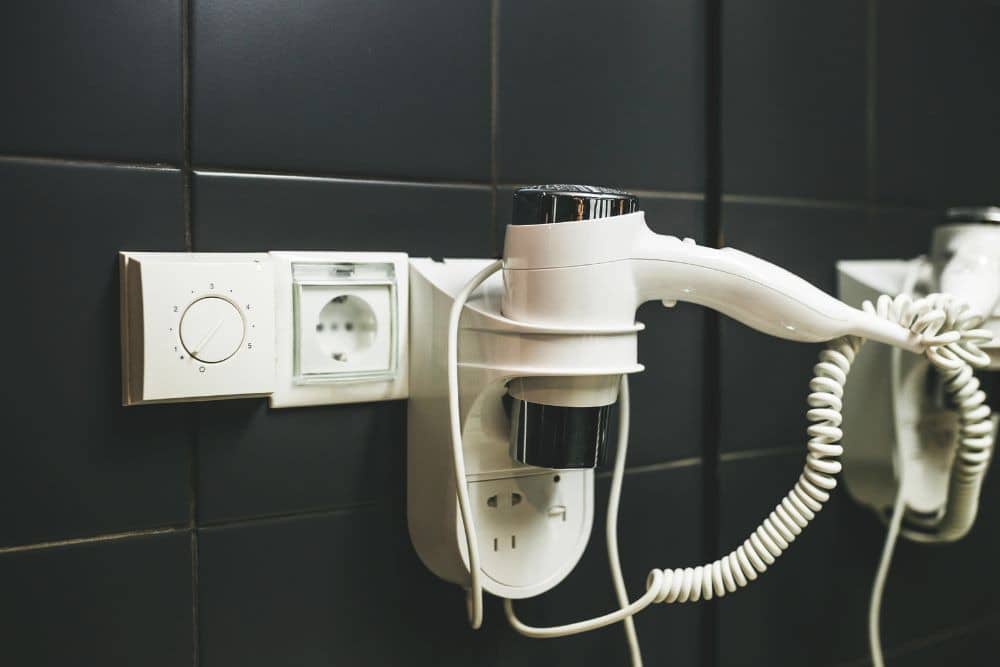 hair dryer on a rest next to a dedicated outlet