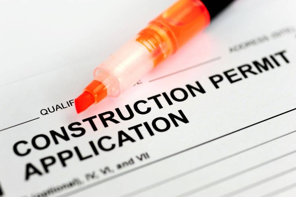 construction permit application form and a neon orange marker.