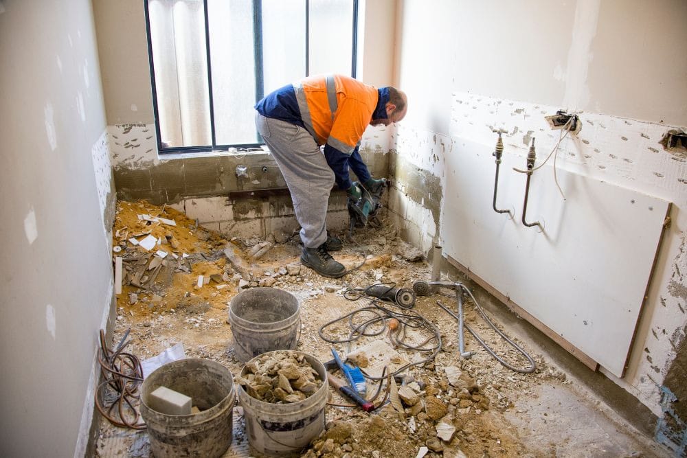 worker performing unexpected repairs on an old bathroom, one of the top hidden costs of bathroom remodeling in seattle
