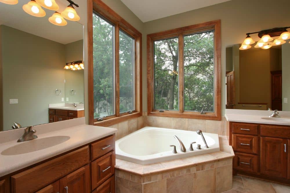 A remodeled bathroom featuring a natural hardwood vanity cabinet and matching wood window accents, showing how to plan a bathroom remodeling project Seattle homeowners can use to bring warmth to their space.