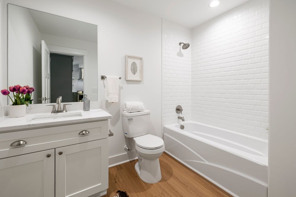 a white modern bathroom with a vanity and corner toilet, illustrating a layout concept for adding a bathroom to your home.